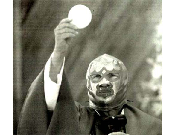 Fr. Fray Tormenta holding the Eucharist while wearing a wrestling mask